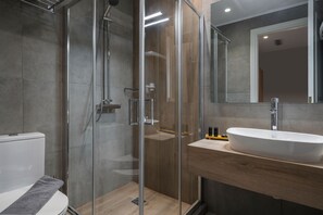 Ein modernes Badezimmer mit einer gläsernen Dusche, einem weißen Waschbecken und einem Holz-Waschtisch.