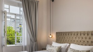 Een hotelkamer met een groot bed, uitzicht op gebouwen en een decoratief plafond.