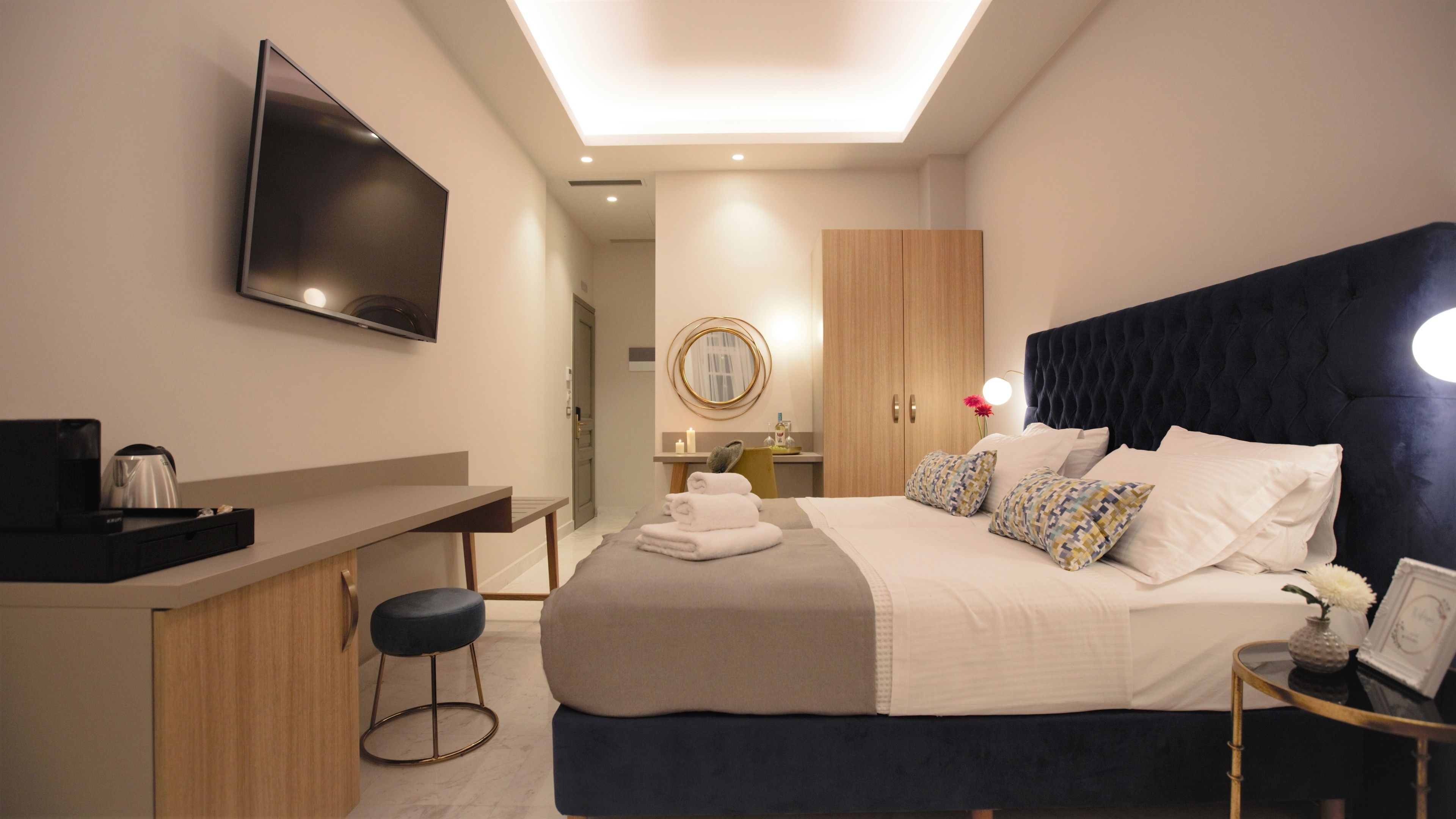 Una habitación de hotel moderna con cama, mesita de noche y escritorio con televisor de pantalla plana.