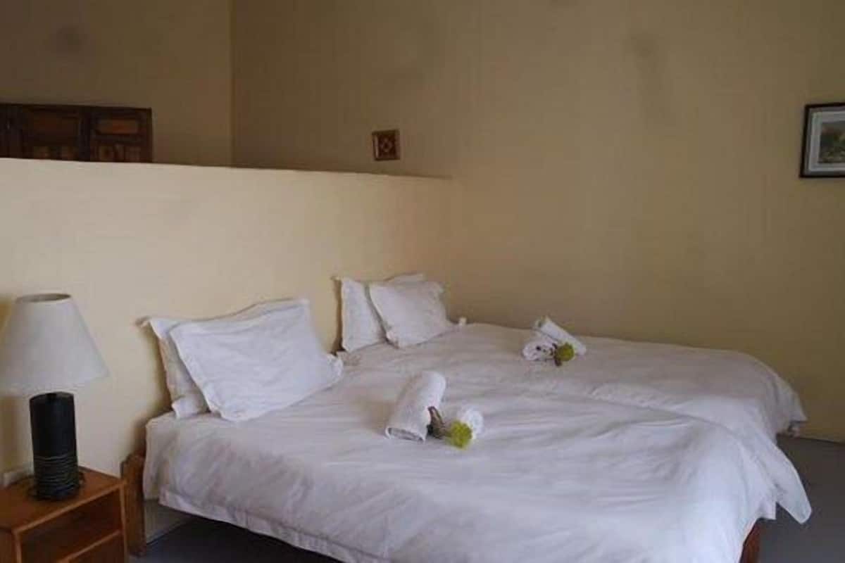 Ein Hotelzimmer mit Bett, Kissen, Nachttisch und Lampe.