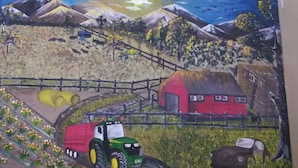 Une fresque représentant une scène de ferme, avec un tracteur, des bottes de foin, une grange et des montagnes.