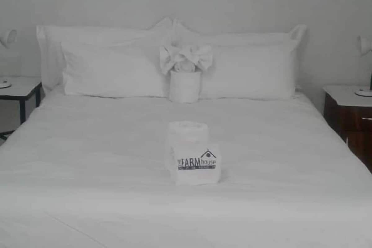 Ein Hotelzimmer mit einem ordentlich bezogenen Bett, einem Nachttisch mit Lampe und einem weiteren Nachttisch ebenfalls mit Lampe.