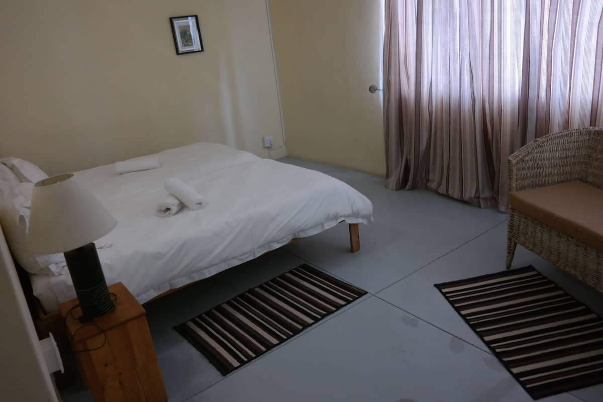 Ein Hotelzimmer mit einem Bett, einem Sessel, einer Lampe und einem Bild an der Wand.