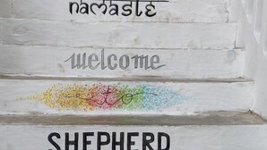 A set of white wooden steps with the words "welcome" and "shepherd" painted on them. - Shepherd Stories - Hostel (Hyderabad)