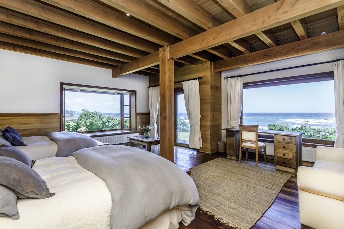 Une chambre avec un grand lit, un bureau et une vue sur l’océan.