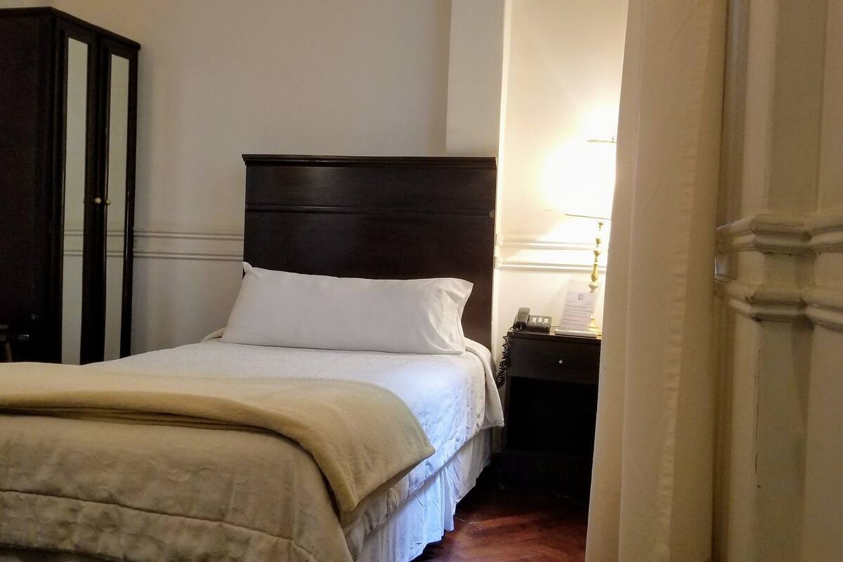 Ein Schlafzimmer mit Bett, Nachttisch, Lampe und Kleiderschrank.