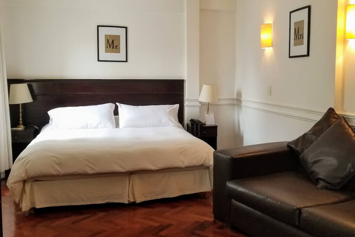 Ein Hotelzimmer mit einem großen Bett, einer Ledersofa und Wandleuchten.