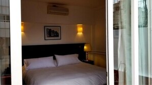 A hotel room with a bed, two bedside lamps, a framed picture on the wall, and a window with curtains. - Hotel San Antonio (Buenos Aires)