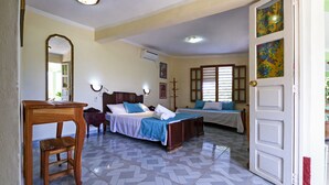 A hotel room with two beds, a desk, a mirror, and a door leading outside. - Hostal MJ (Trinidad)