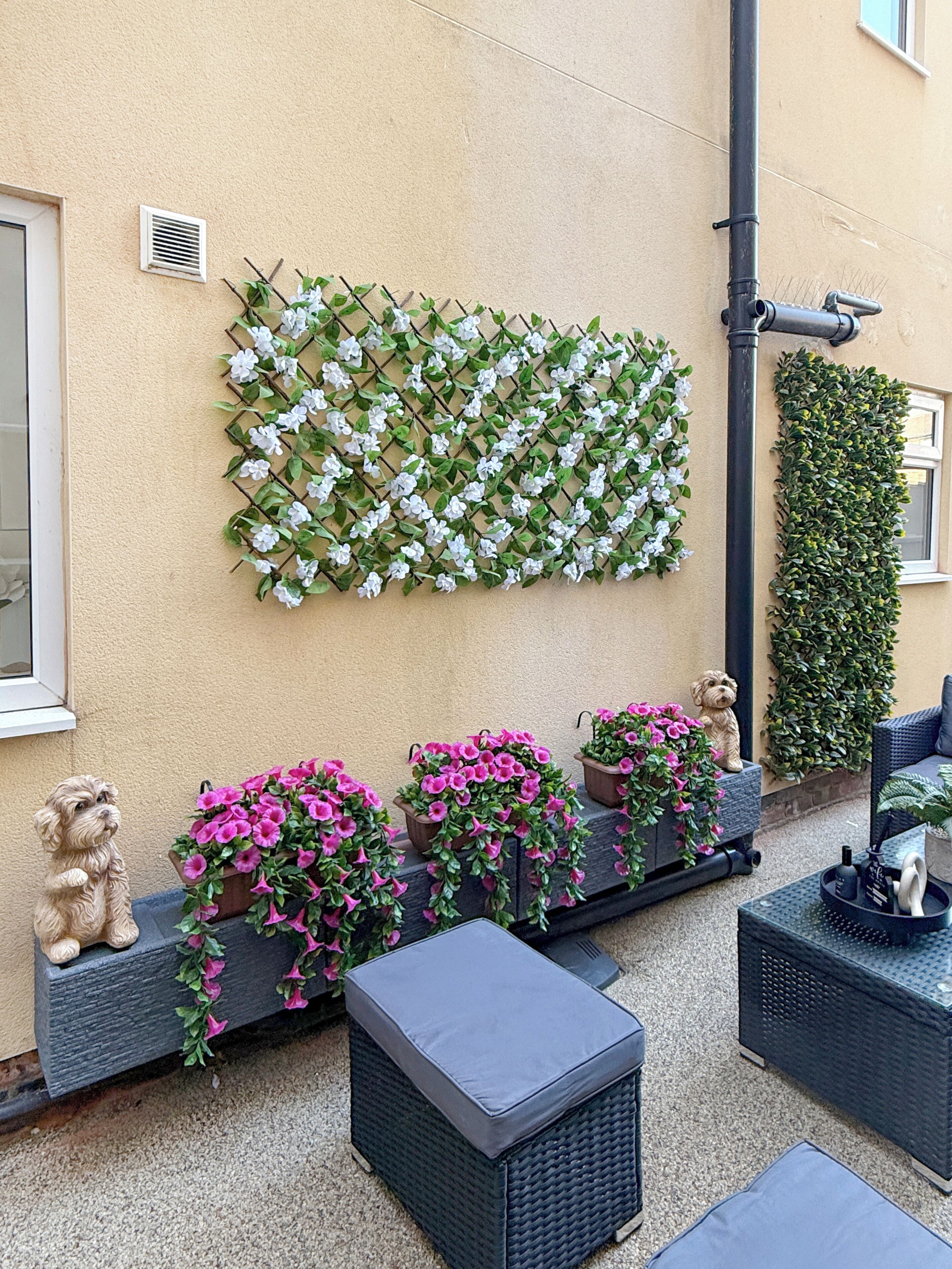 Eine Terrasse mit Gartenmöbeln, Topfpflanzen und Dekoration.
