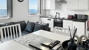 Una cocina moderna con armarios blancos, microondas y estufa. Hay un comedor con una mesa blanca y un mantel decorado.