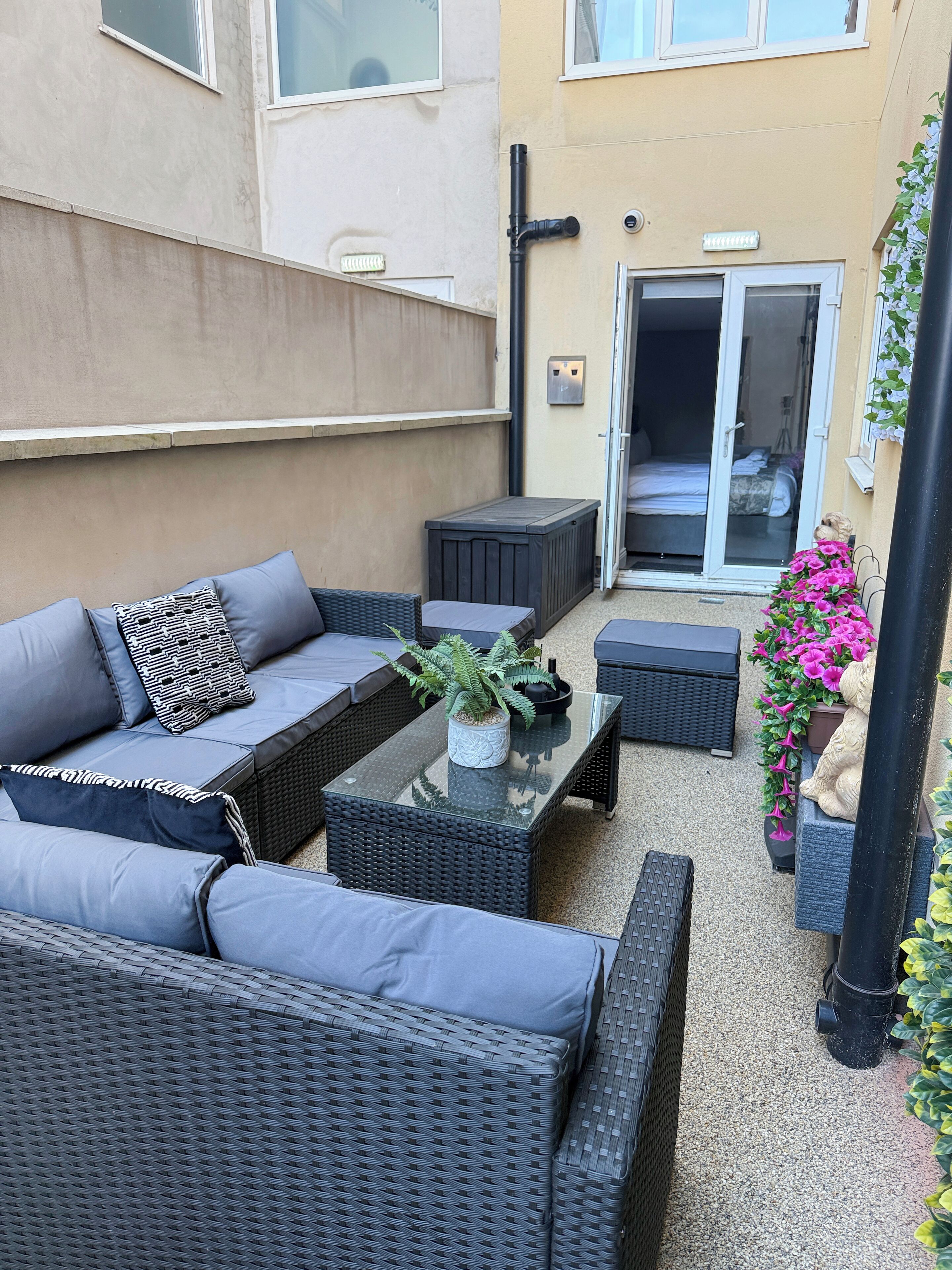 A patio area with a sofa set, a coffee table, and a potted plant.