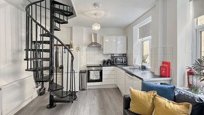 Una cocina moderna con escalera de caracol, muebles blancos y encimera negra.