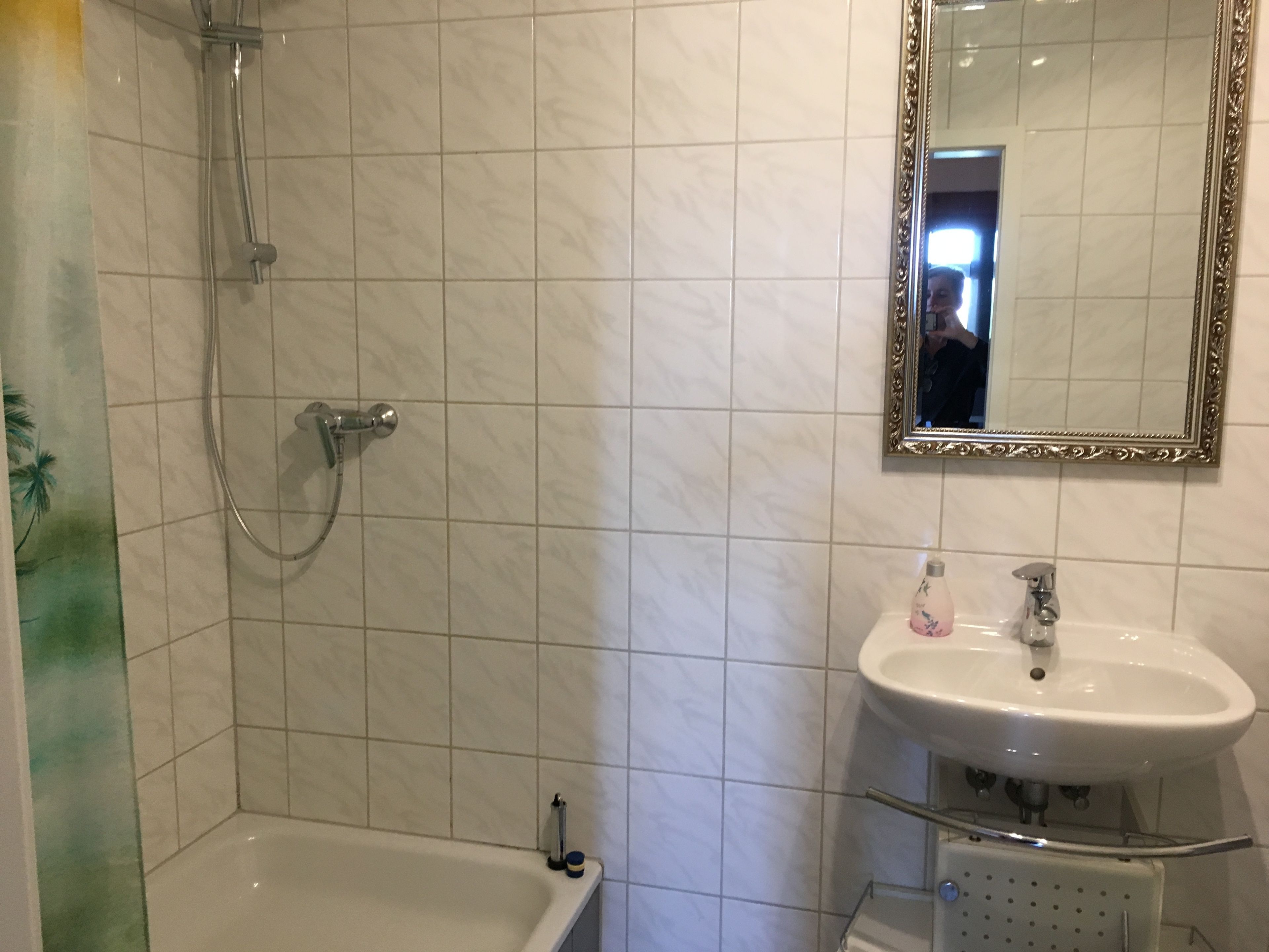 A bathroom with a shower, a sink, and a mirror.