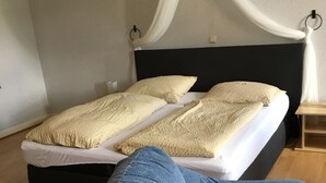 A bedroom with a bed, a nightstand, and a blue chair. - Gästehaus zur Post (Wabern)