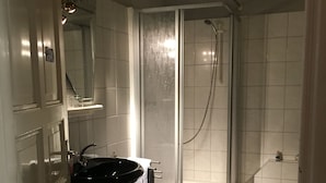 A bathroom with a black sink, a shower enclosure, and tiled walls. - Gästehaus zur Post (Wabern)