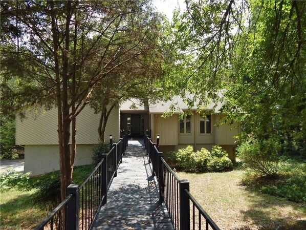A pathway leading to a building with a covered walkway and a fence.