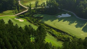 A golf course with a winding path, sand bunkers, and dense trees. - Beautiful Balboa Waterfront! (Hot Springs Village)