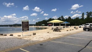 A beach with a parking area, picnic tables, and umbrellas. - Beautiful Balboa Waterfront! (Hot Springs Village)