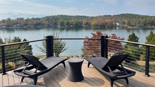 A deck with two lounge chairs and a small table, overlooking a lake with a forested shoreline. - Beautiful Balboa Waterfront! (Hot Springs Village)