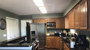 A kitchen with wooden cabinets, stainless steel appliances, and a microwave. - Beautiful Balboa Waterfront! (Hot Springs Village)