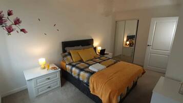A bedroom with a bed, nightstands, a mirror, and a door.