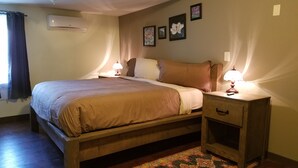 Un dormitorio con cama de madera, lámparas de noche, una mesita de noche y una alfombra estampada.