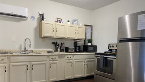Una cocina moderna con armarios blancos, electrodomésticos de acero inoxidable y piso de madera oscura.