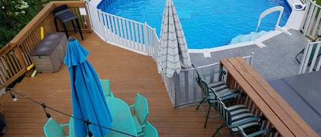Una piscina circular con una terraza de madera, rodeada por una cerca blanca.