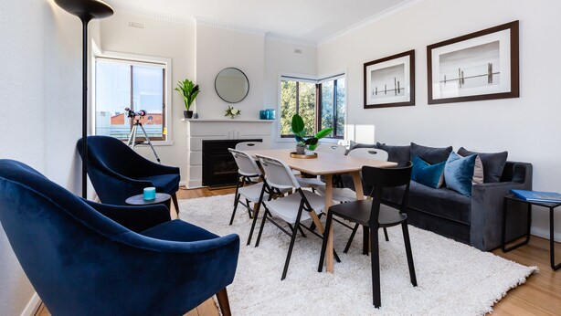 A modern living room with a dining area, a fireplace, and a large window. - Lighthouse Cozy 2BDR with CITY VIEWS (Middle Park)