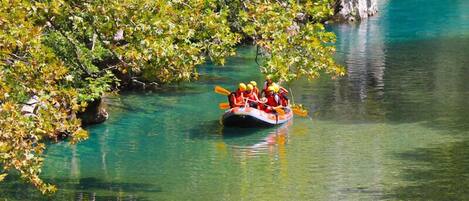 Un grupo de personas en una balsa navegando por un río cristalino rodeado de exuberante vegetación y riscos rocosos.