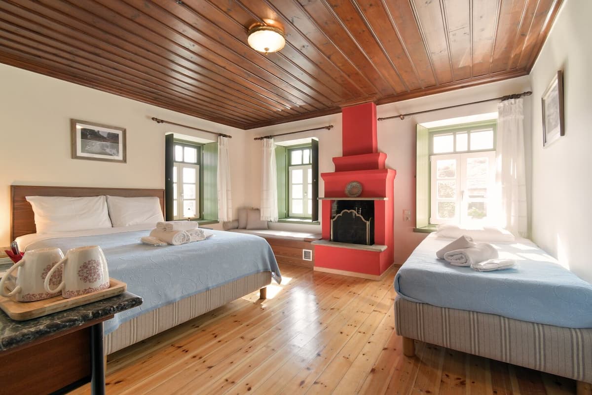 Ein Hotelzimmer mit zwei Betten, Holzboden, einem roten Kamin und großen Fenstern.