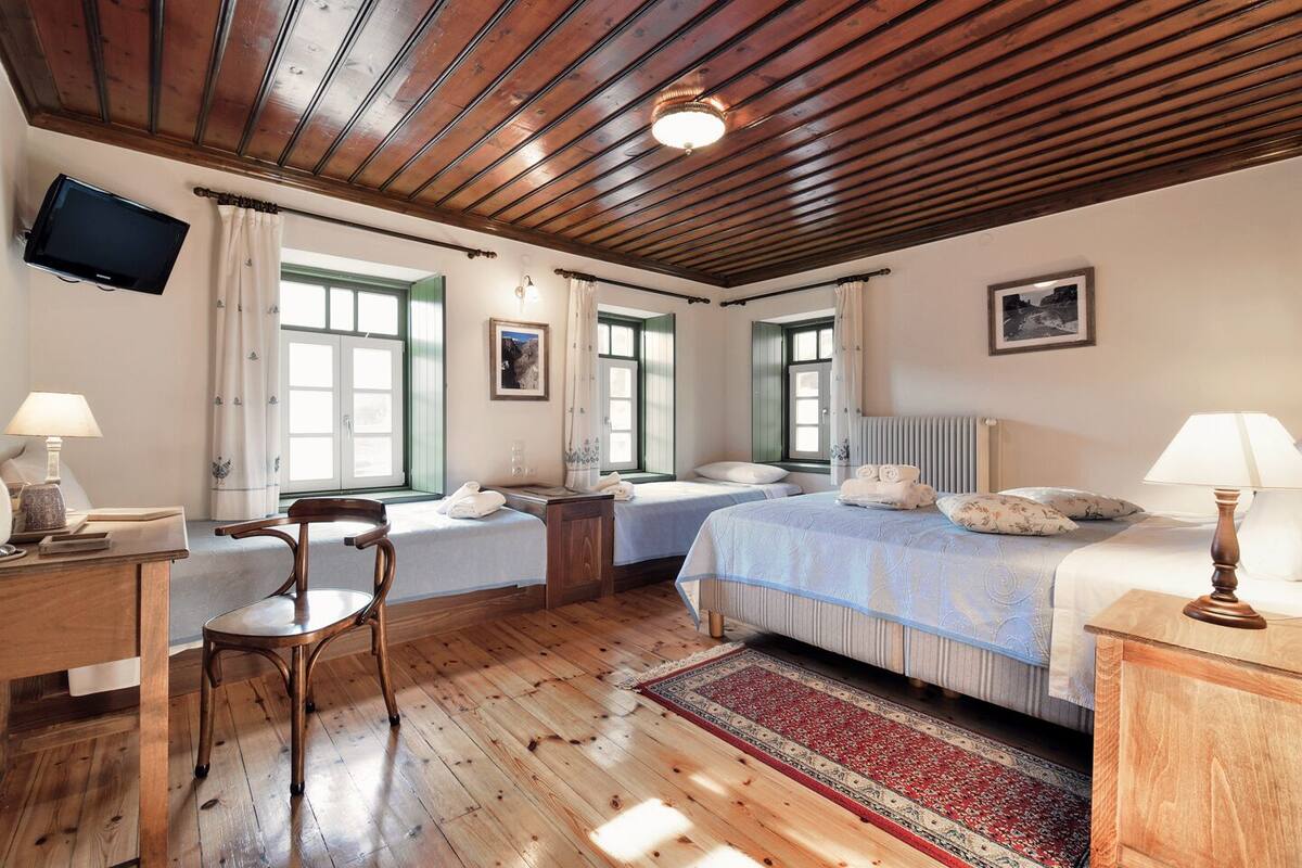 Ein Zimmer mit zwei Betten, einem Schreibtisch, einem Stuhl, einem Fernseher und einer Heizung.