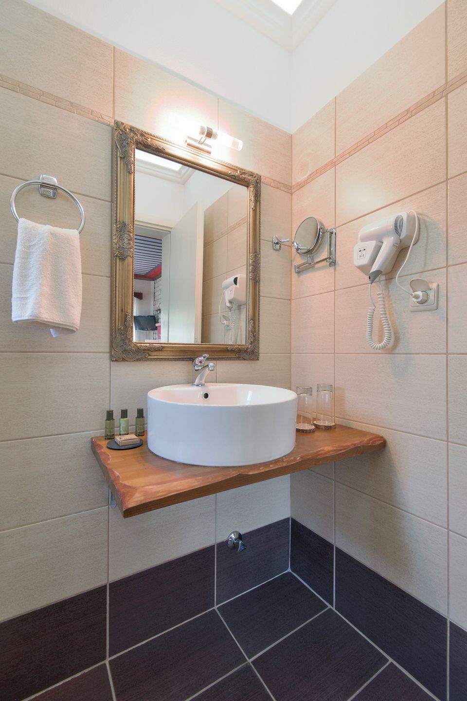 Une salle de bain avec un lavabo blanc, un miroir, un sèche-cheveux et un porte-serviettes.