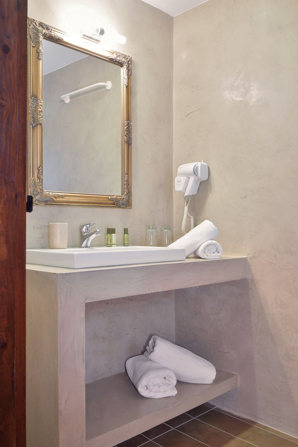 Un baño con lavamanos, espejo, toallero y secador de pelo.