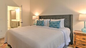 Un dormitorio ordenado con una cama grande, lámparas de noche y una mesita de noche de madera.
