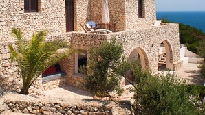 A stone building with a terrace, outdoor seating, and a view of the sea. - Villa La Mecca Leuca Seaside villa with pool (Gagliano del Capo)