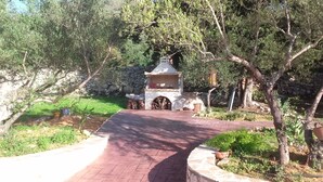 Un sendero pavimentado que conduce a una estructura de piedra con chimenea, rodeada de árboles y follaje.