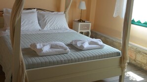 Una cama con dosel con sábanas blancas y un dosel, una mesita de noche con lámpara y una decoración de pez en la pared.