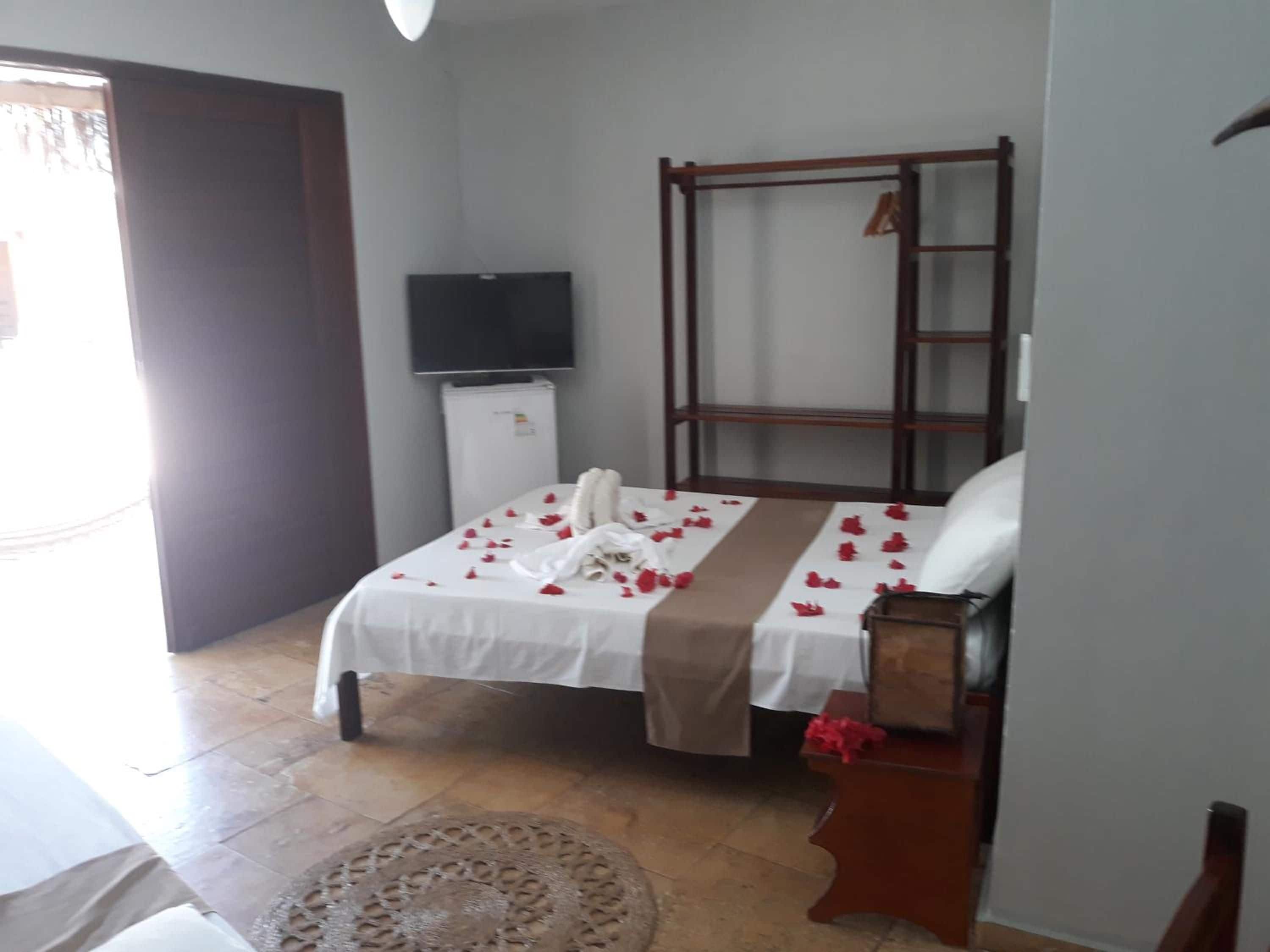 A hotel room with a bed, a television, a wardrobe, and a small refrigerator.