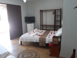 Una habitación de hotel con cama, televisión, armario y un refrigerador pequeño.