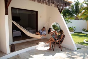 Una hamaca en un espacio exterior cubierto, con una cama y una silla.