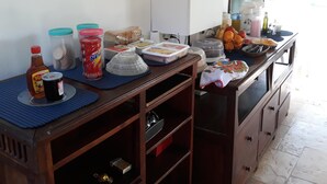 A kitchen area with a refrigerator, a chalkboard, and various food items and containers on the counter. - Pousada Porto Azul (Caucaia)