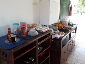 Un área de cocina con refrigerador, una pizarra y varios alimentos y recipientes sobre la encimera.