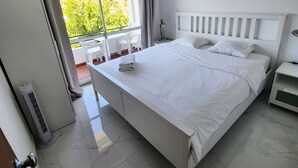 Moderni hotellihuone, jossa on suuri sänky, parveke, jolta on näkymä, ja seinälle asennettu ilmastointilaite.