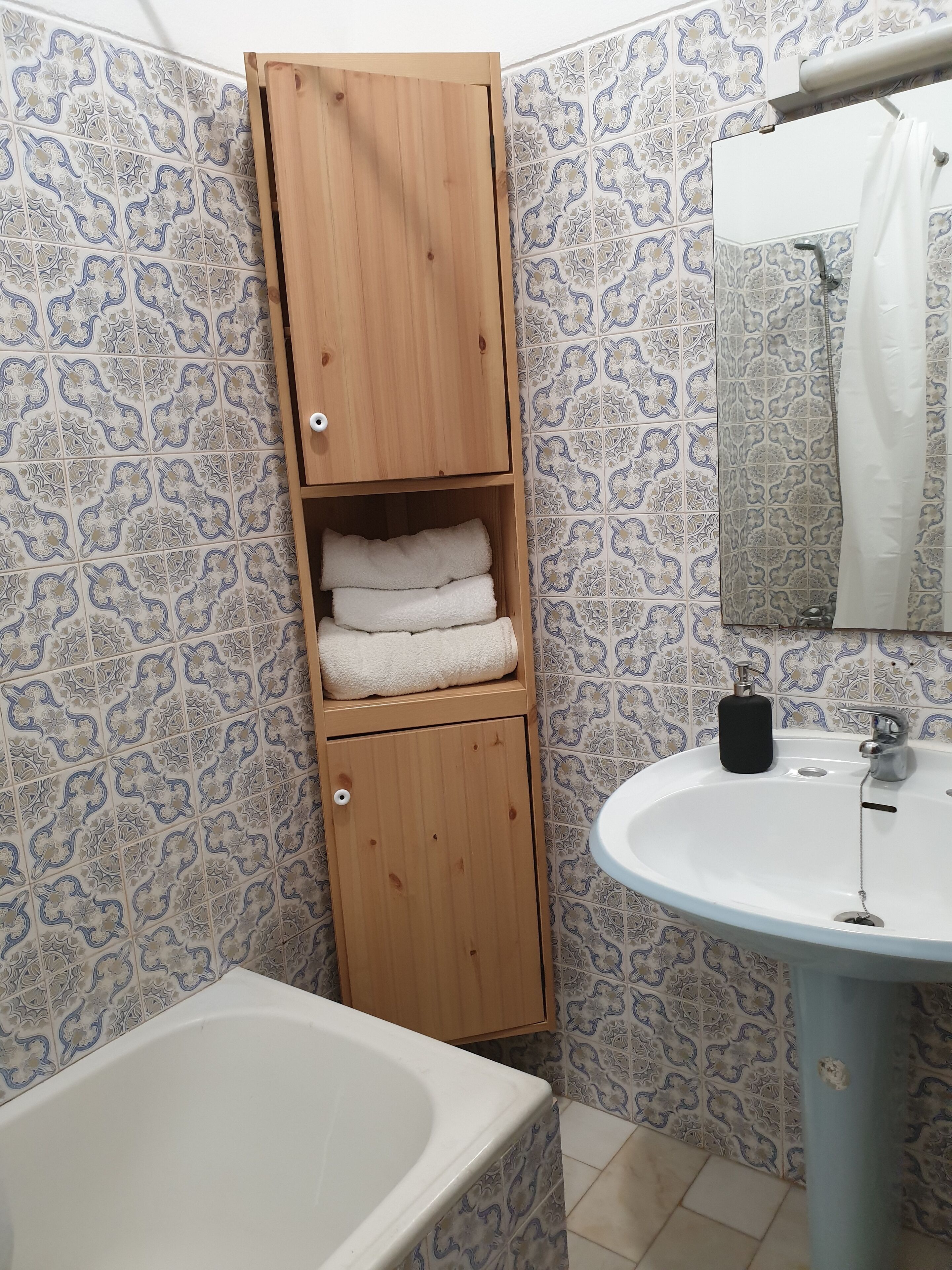 Un baño con un mueble de madera, un lavamanos y una bañera.