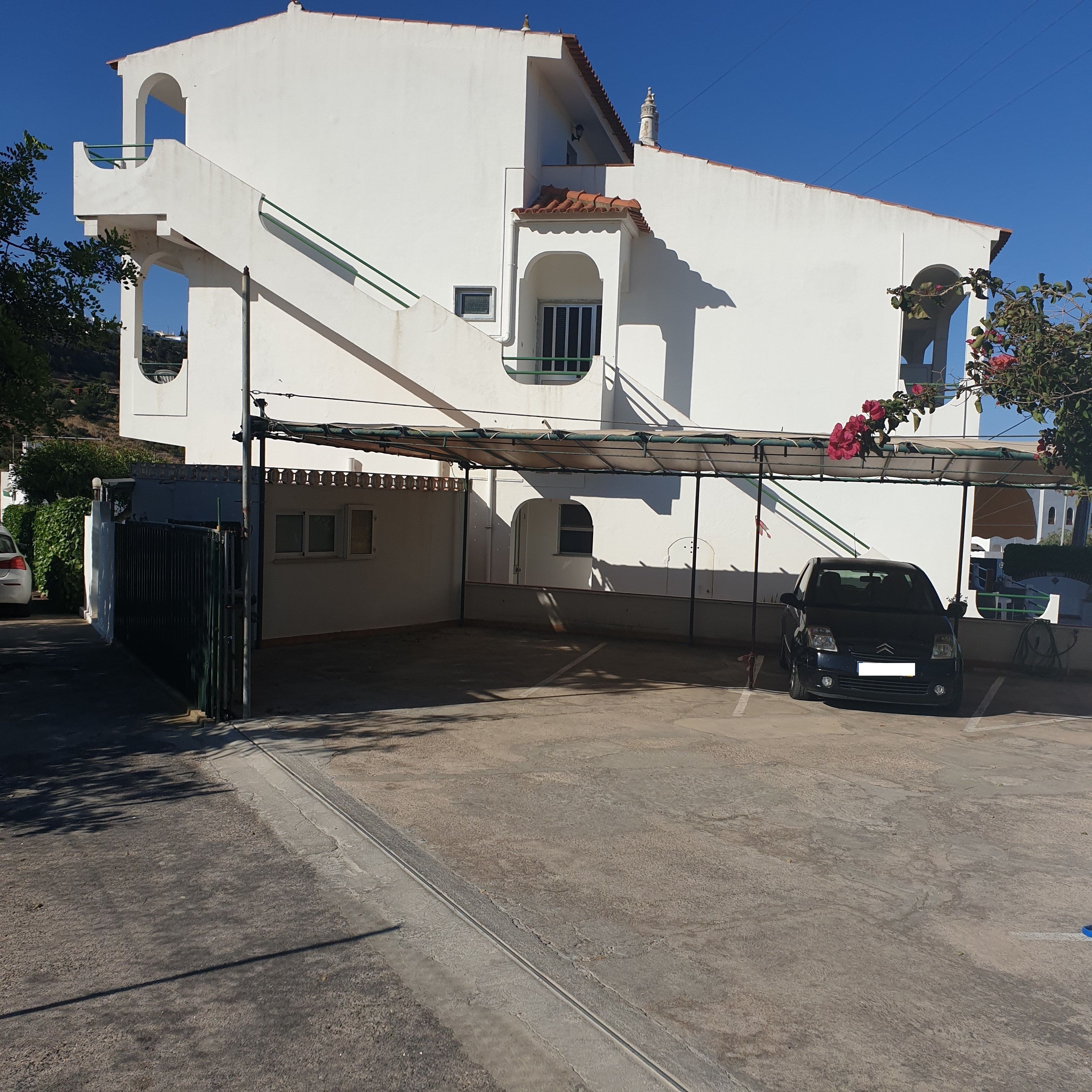 A white building with a covered parking area and a car parked inside.