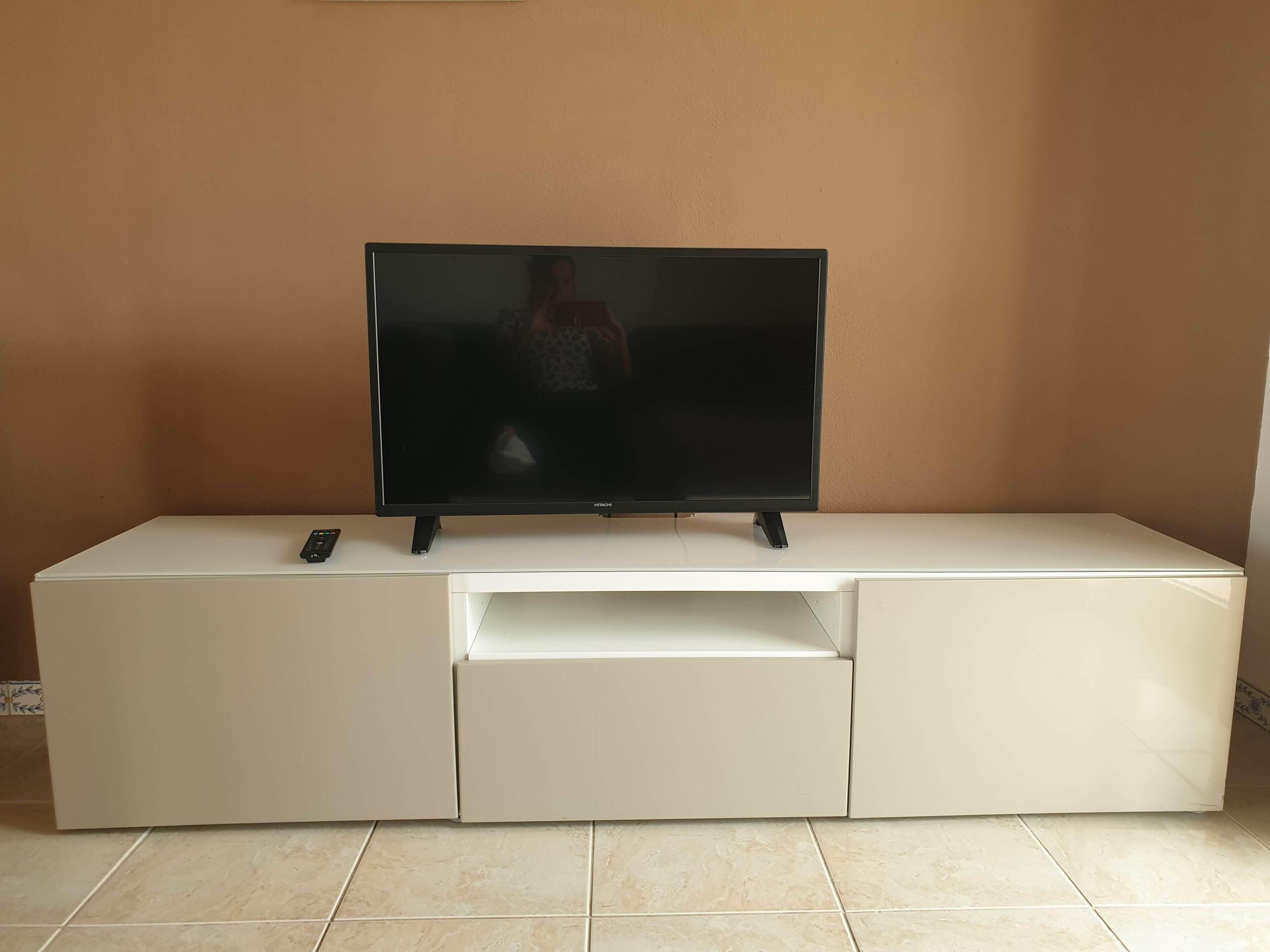 A flat-screen TV on a white entertainment unit with a remote control.