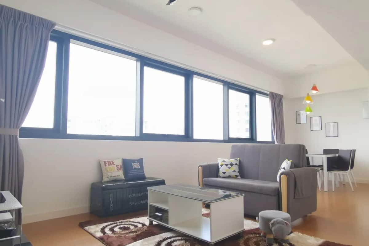 A modern living room with a grey sofa, a coffee table, and a patterned rug.