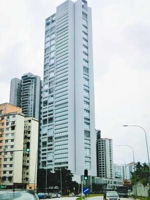 A tall, modern high-rise building with a grid of windows and balconies.